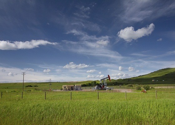 Beautiful landscape with green grass, blue sky and pumpjack. Pho